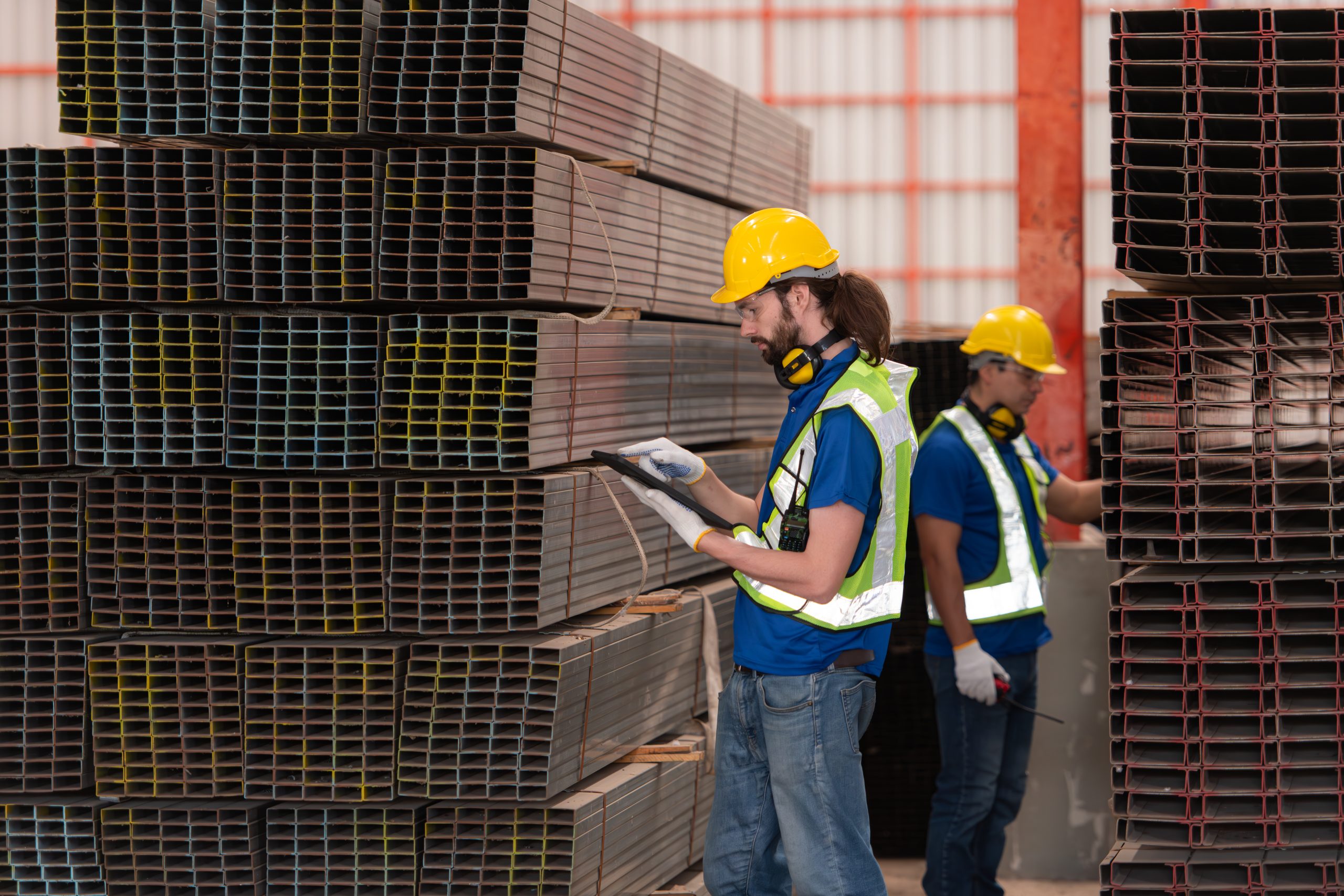Warehouse workers in hard hats and helmets stand in the warehous